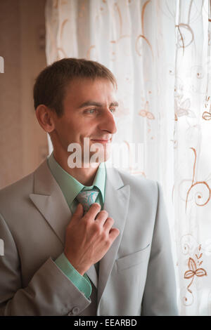 Portrait of young groom tying tie while getting  ready for wedding Stock Photo