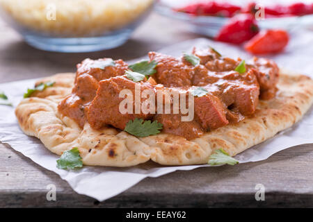 A delicious butter chicken curry served on naan bread with saffron basmati rice. Stock Photo