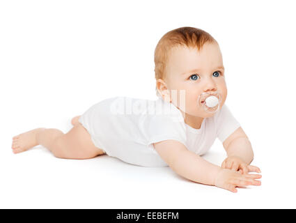 smiling baby lying on floor with dummy in mouth Stock Photo