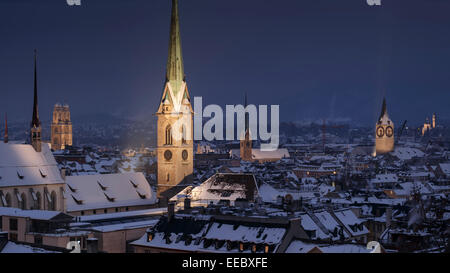 The old town with snow-covered roofs at night, with the illuminated Gothic bell towers, Zurich, Switzerland. Stock Photo