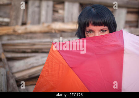 Young woman peeping from behind the umbrella. Stock Photo