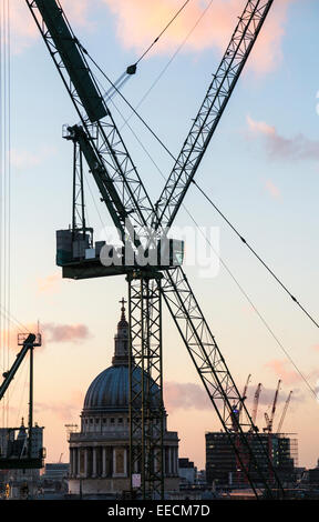 Tower cranes on the Bloomberg building site in the City of London EC4 above the distant dome of St Paul's Cathedral Stock Photo