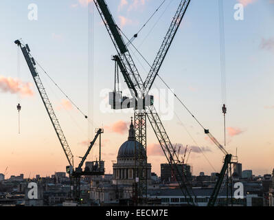 Tower cranes on the Bloomberg building site in the City of London EC4 above the distant dome of St Paul's Cathedral Stock Photo