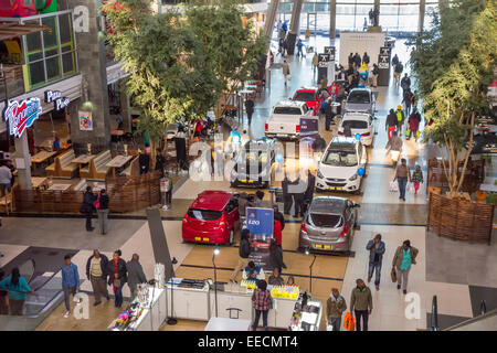 SOWETO, JOHANNESBURG, SOUTH AFRICA - Shoppers walk by new cars on display at Maponya Mall shopping center. Stock Photo