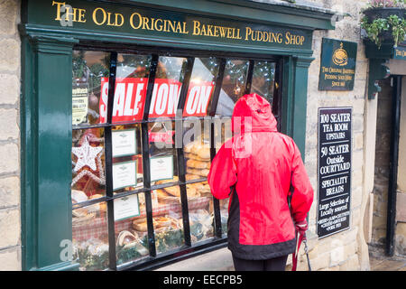 lady looking into the shop window of the old original bakewell pudding shop in historic bakewell in the derbyshire peak district Stock Photo