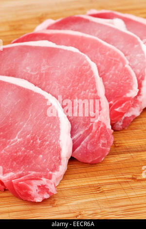 Raw pork lion on wood cutting board cut into chops Stock Photo