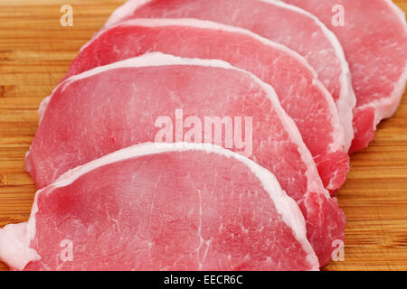 Raw pork lion on wood cutting board cut into chops Stock Photo