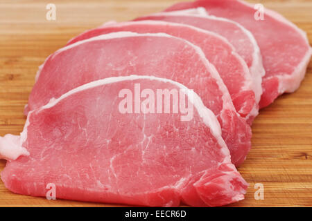 Raw pork lion on wood cutting board cut into chops Stock Photo