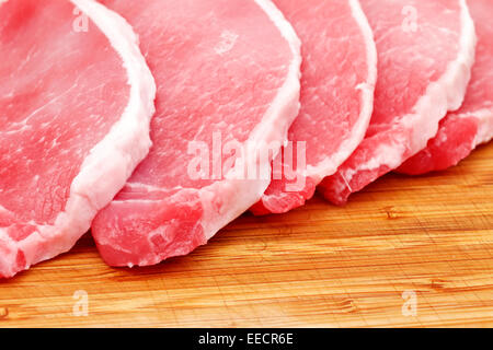 Raw pork lion on wood cutting board cut into chops Stock Photo