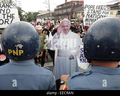 Manila, Philippines. 16th January, 2015. A Pope Francis standee stands between activists and policemen. Activists belonging from various cause-oriented groups hoping to personally welcome Pope Francis were blocked by policemen from approaching Ayala Bridge where the His Holiness' convoy went after a courtesy call to Malacanang Palace. Credit:  Richard James Mendoza/Pacific Press/Alamy Live News Stock Photo