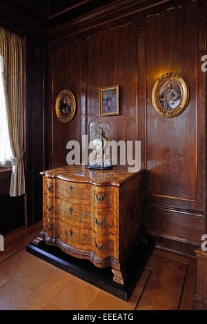 The Duchess s Salon is panelled in the neo-Rococo style with its original red wall coverings, woven French silk from the 18th century. The commode from this period belonged to the Duke s family. Portraits of Ernst and Alexandrine and one of Prince Albert Stock Photo