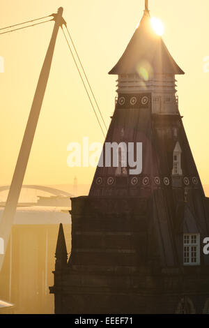 The sun rises behind the market tower of Newport City, the Millennium bridge and the New City Bridge can be seen. Stock Photo