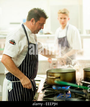 Chefs and kitchen staff working in a busy kitchen Stock Photo