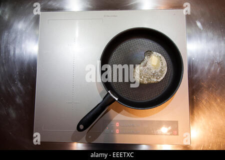 Butter melting in non-stick pan on induction hob Stock Photo