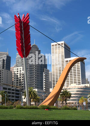 'Cupid's Span' a giant bow and arrow sculpture on the Embarcadero with man lying on grass San Francisco California USA Stock Photo