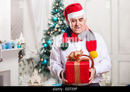 Senior man holding a red gift box on Christmas background Stock Photo