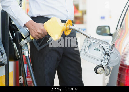 Close up Asian man pumping gasoline fuel in car at gas station. Stock Photo