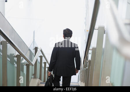 Rear view of an Asian Indian businessman with briefcase descending steps. Stock Photo