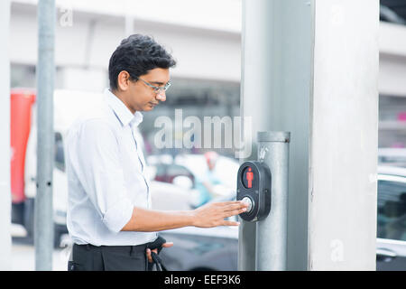 Asian Indian people hand pushing a crosswalk button at a traffic signal. Stock Photo