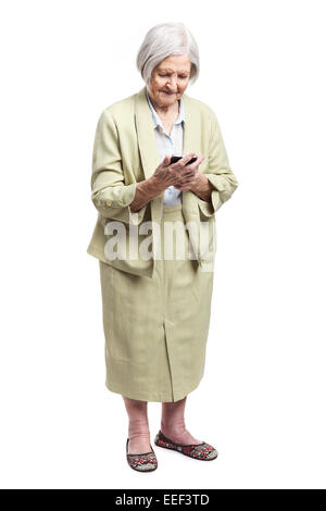 Senior woman using mobile phone while standing over white background Stock Photo