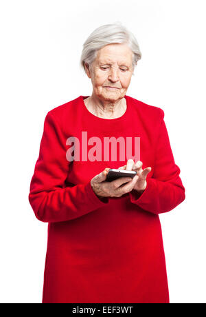 Senior woman using mobile phone while standing over white background Stock Photo