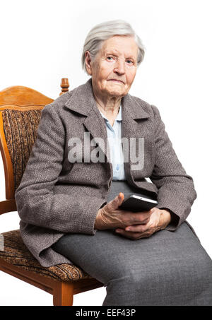 Senior woman sitting on chair and holding mobile phone Stock Photo