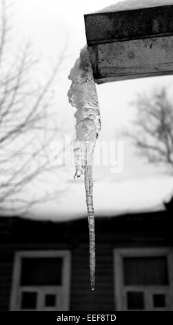 A large icicle hanging from the roof of the house photographed closeup Stock Photo