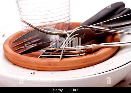 A stack of dirty plates, forks, knifes and a glass that needs washing-up. Stock Photo