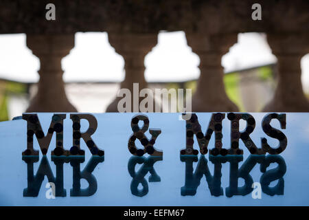 'Mr & Mrs' sign on reflective table overlooking the wedding venue gardens Stock Photo