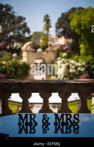 'Mr & Mrs' sign on reflective table overlooking the wedding venue gardens Stock Photo