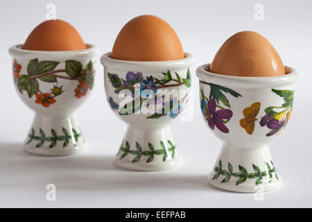 Three Portmeirion pottery egg cups with eggs in isolated on white background Stock Photo