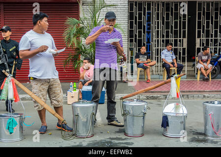 Intramuros, Manila, Philippines, 16th Jan 2015. Taho vendors eat their breakfast on Friday, January 16, 2015 in front of their aluminum buckets near Manila Cathedral, Intramuros, where they expect thousands of Filipinos to gather and get a glimpse of Pope Francis who was scheduled to celebrate Holy Mass with the country's bishops, priests, and other religious. Credit:  tonyoquias/Alamy Live News Stock Photo