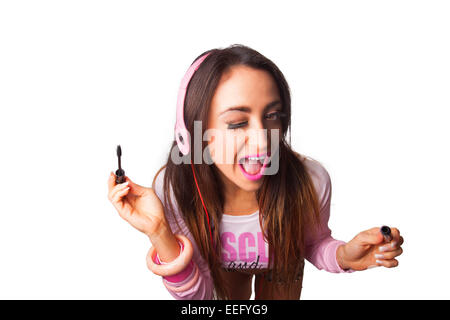 Young Pretty Latino Woman Putting on mascara while listening to Headphones Stock Photo