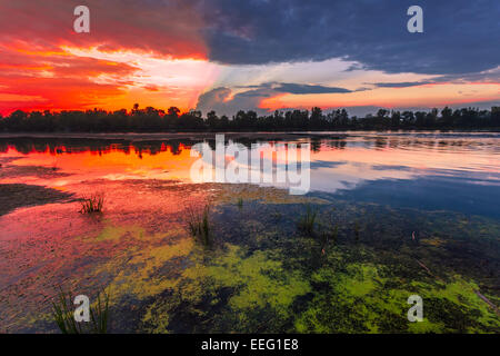 Amazingly colorful sunset with reflective red sand and bright clouds Stock Photo