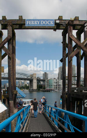 Ferry dock and passengers, Granville Island, Vancouver, British Columbia. In the distance can be seen the Burrard Bridge Stock Photo