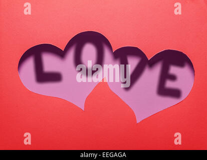 Two hearts cutout in red paper with word "LOVE" inside.Card design. Stock Photo