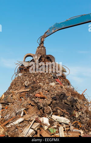 crane holding rusty metal in recycling junkyard Stock Photo