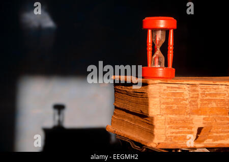 antique old used book bible and red broken sandglass hourglass Stock Photo