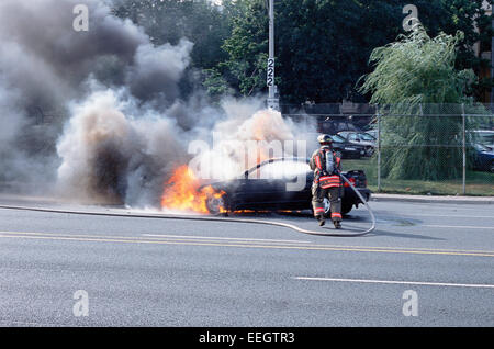 Fireman putting out car fire in toronto Ontario Stock Photo