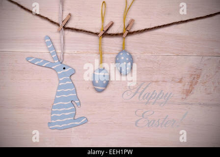 One Blue Easter Bunny With Stripes Hanging On A Line With Two Blue Easter Eggs Which Are Dotted And Striped On White Wooden Vint Stock Photo