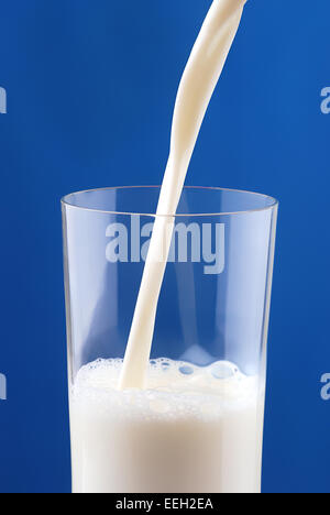 Pouring milk on blue background Stock Photo