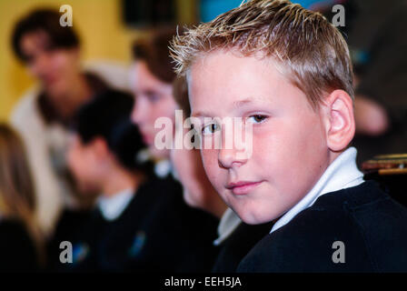Boy in classroom with schoolteacher in background Stock Photo