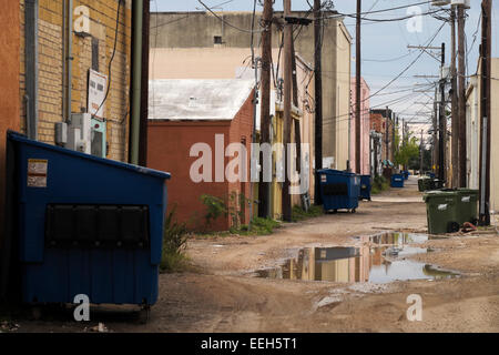 Back alley in downtown Weslaco, Texas after a rain storm left standing puddles in the caliche roadway. Stock Photo