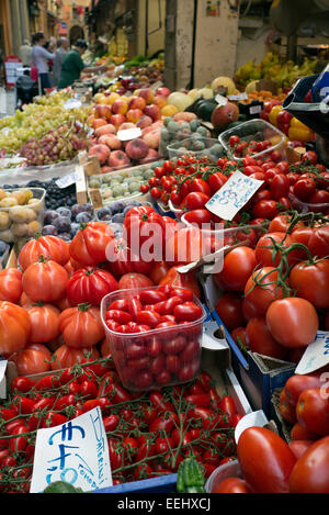 A fruit stall in Bologna, Italy. There are tomatoes in the foreground and many other types of fruits in the background. Stock Photo