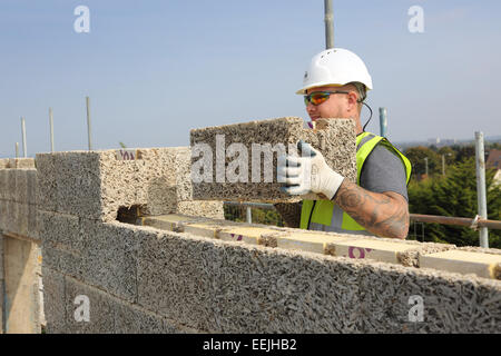 A workman positions a Durisol cement-bonded wood fibre block whilst building an apartment block in West London. Stock Photo