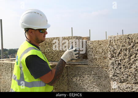 A workman positions a Durisol cement-bonded wood fibre block whilst building an apartment block in West London. Stock Photo