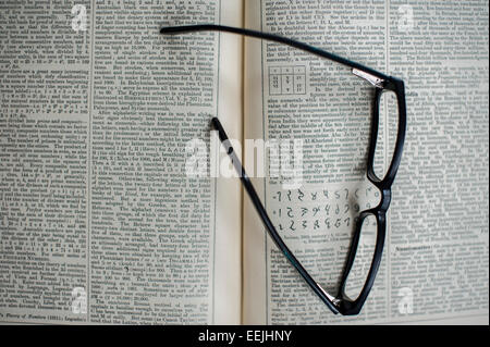 Pair of reading glasses resting on an open encyclopaedia