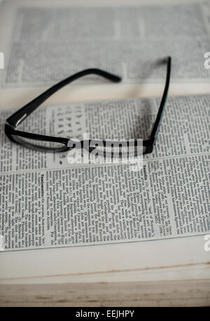 Pair of reading glasses resting on an open encyclopaedia