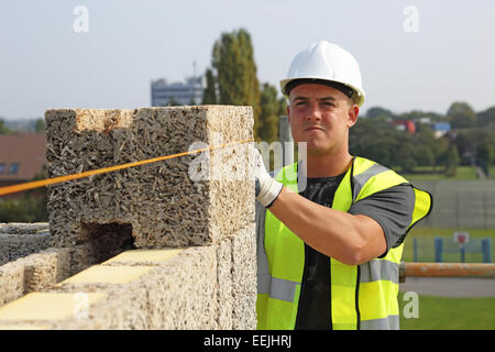 A workman uses a line to check the level of Durisol cement-bonded wood fibre blocks whilst building an apartment block. Stock Photo