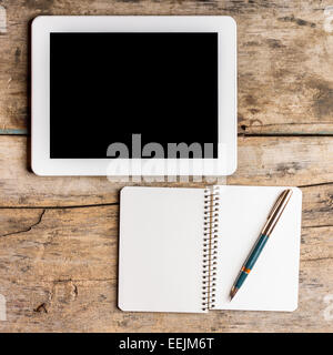 Digital pad with empty black screen and opened notebook with old fountain pen on wooden table Stock Photo